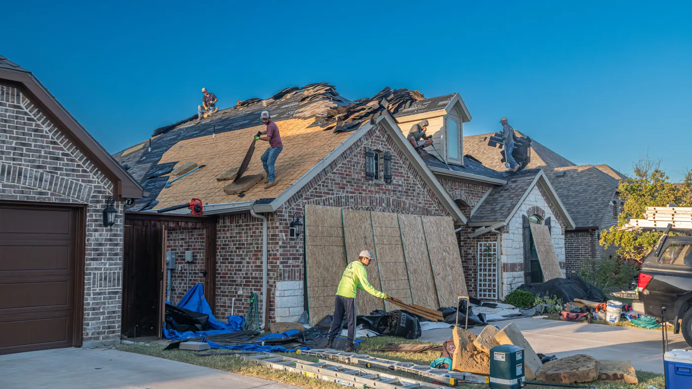 Roofing crew removing shingles from a residential roof