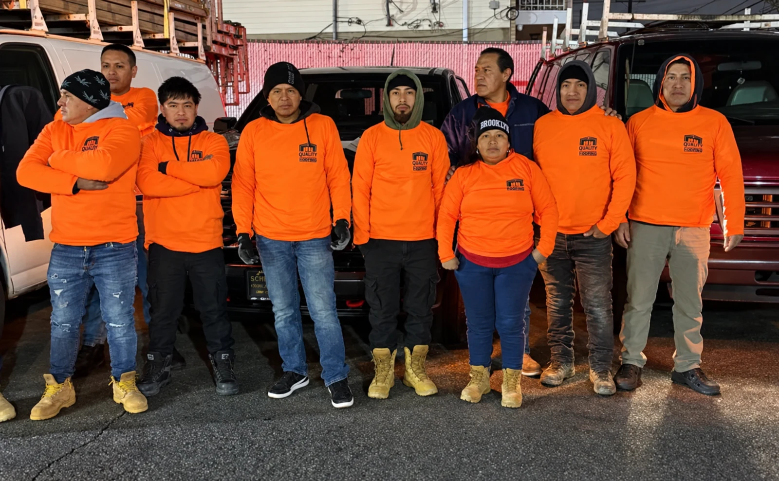 Remodeling and Quality Corp team wearing orange work shirts beside their work vehicles